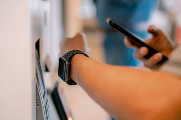 Asian man using smartwatch for contactless paying at vending machine.